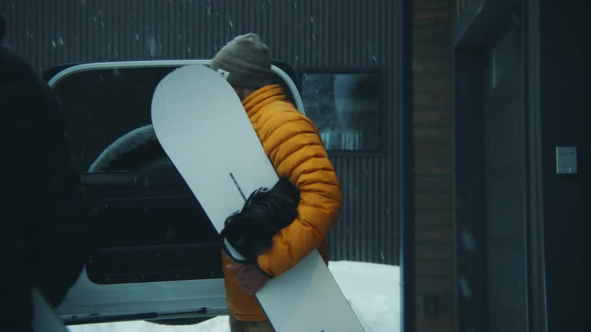 Two men are loading up snowboards in a vehicle