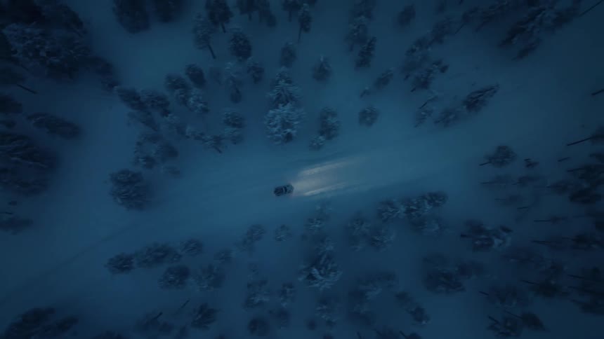 There is a car driving outside down the road in the winter time