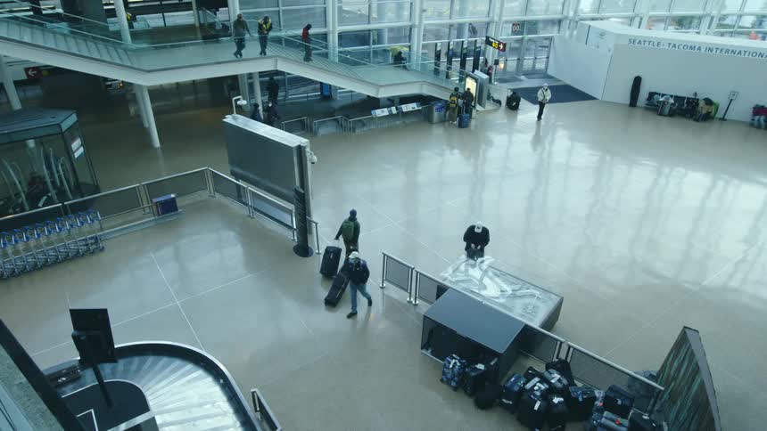 Some people stand while others fetch their luggage or move through the terminal