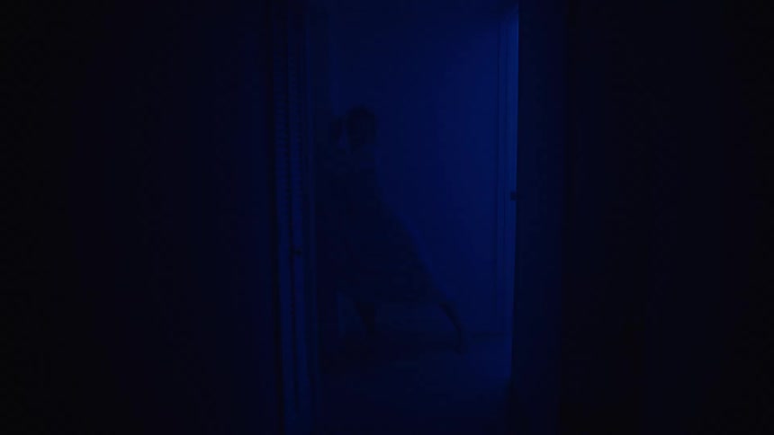A scared silhouetted woman running through a dark hallway