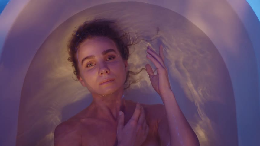 A woman floating in her tub with light shimmering on her