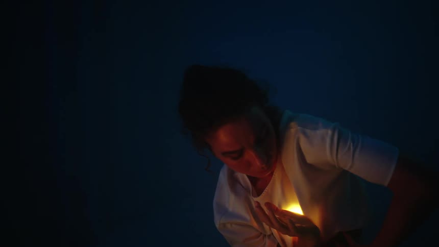 A woman is dancing outdoors with an orb of light