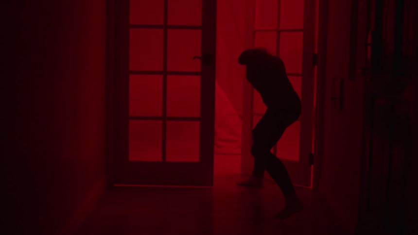 A silhouette woman struggling to close a french door in a haunted house