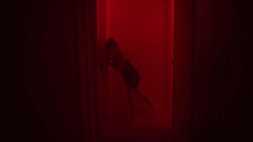 A scared woman is running through a house at night