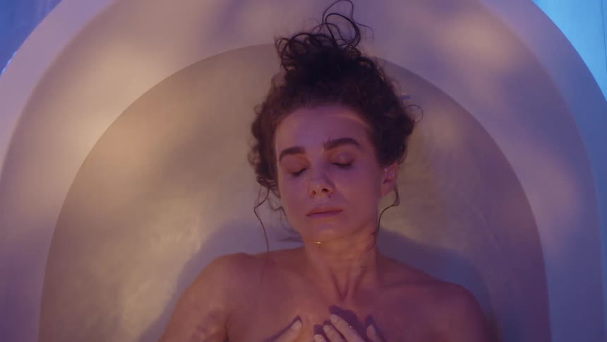 A woman is laying down in a bathtub filled with water