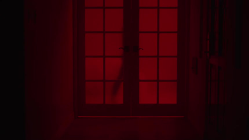 A person is dancing behind the closed door in a red room