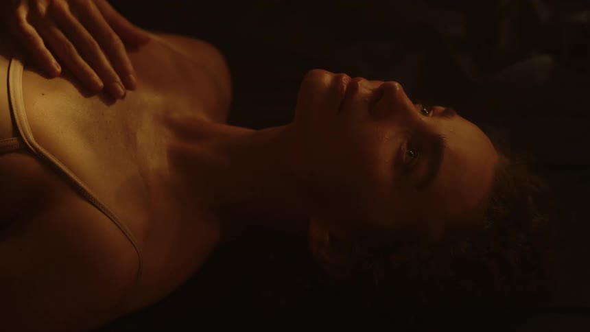 A woman lays on her back as light reflecting off of water is cast upon her face