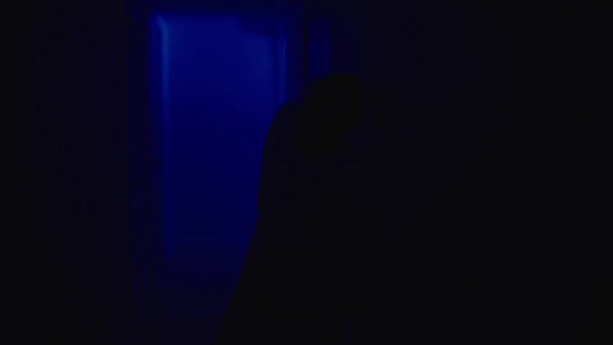 The silhouette of a woman moving in a dark room
