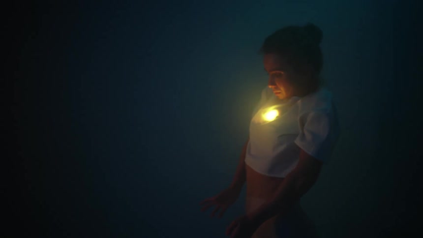 A young woman dancing with a flare under her shirt
