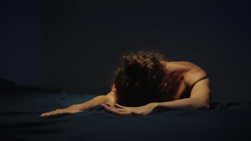 A woman with bare shoulders and arms rubbing her hands on dark fabric