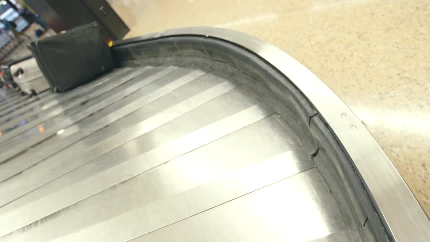 Metal conveyor belt moves luggage at luggage claim area of transport terminal