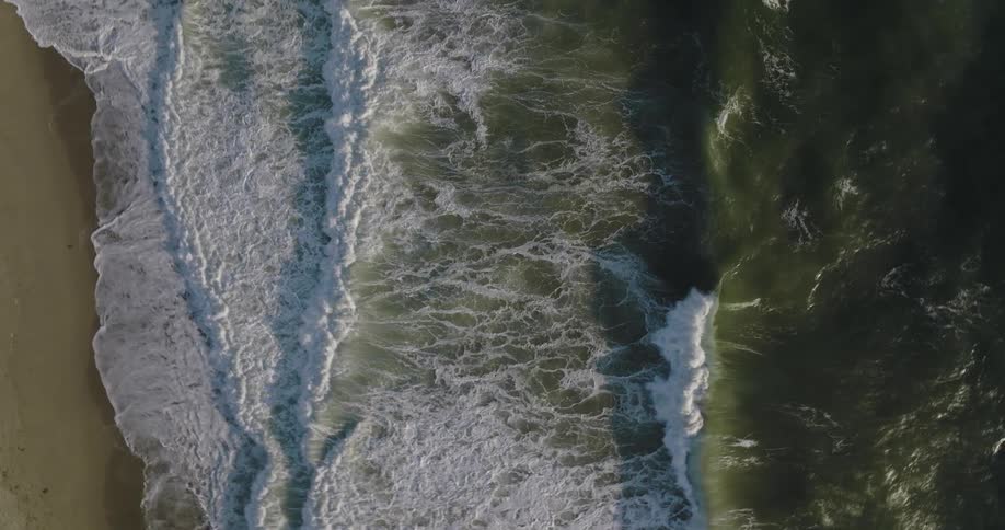 Waves splash and foam as the roll in over a beach