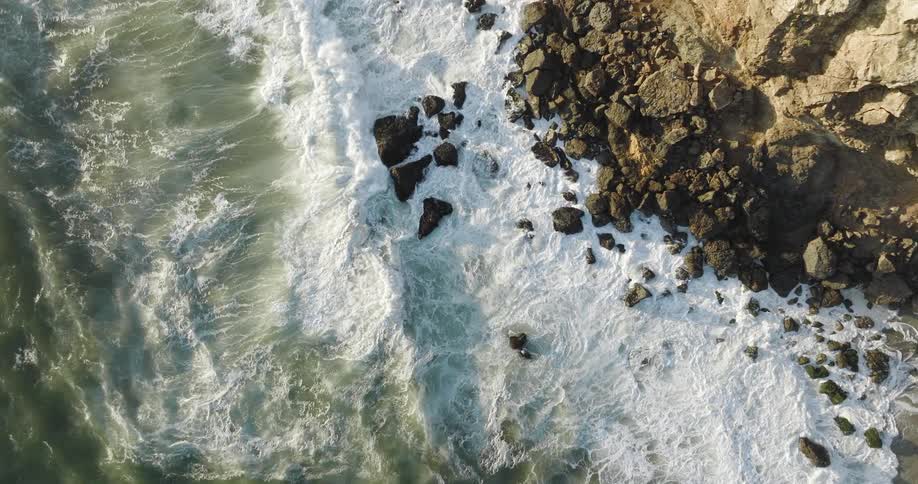 Aerial view of ocean waves moving towards the coast is displayed