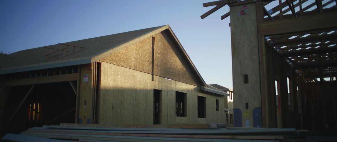 Stacks of lumber sitting in front of partially constructed homes and structures
