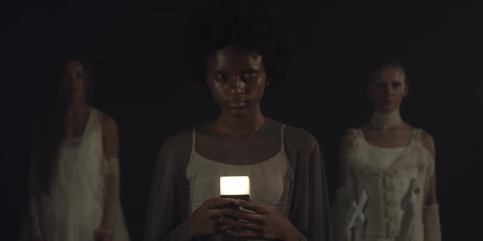 Woman holds electric light source as she and two other women stand in dark area