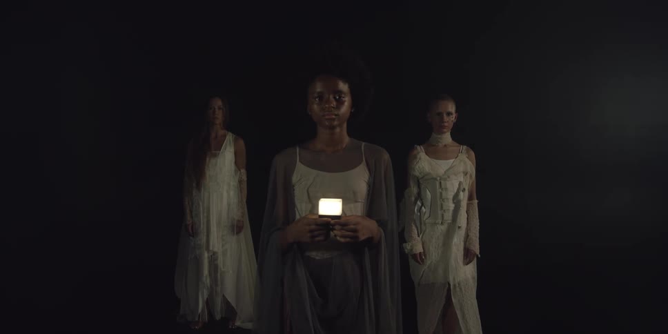 A model holds a lamp while standing in front of a pyramid formation