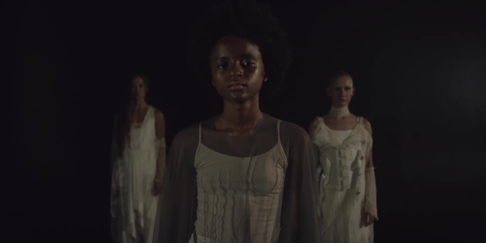 Three women stand together in the dark