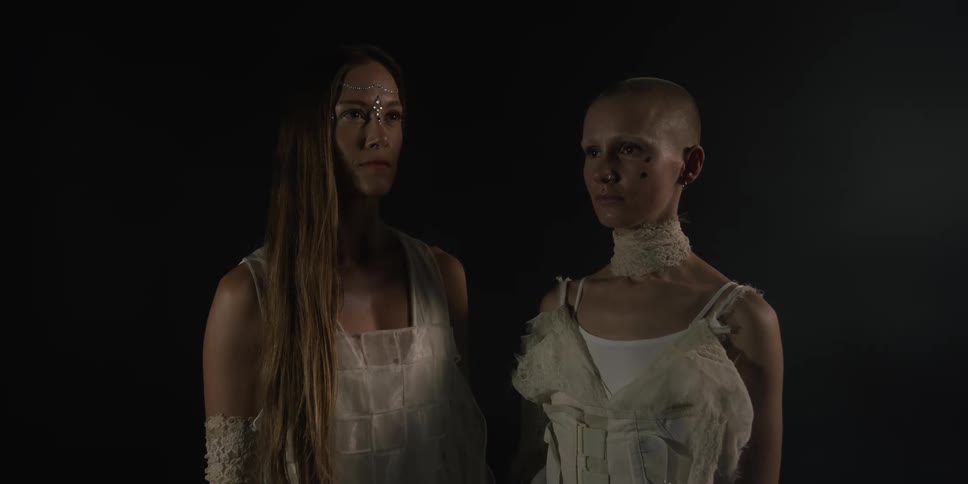 Two women stand together in the dark