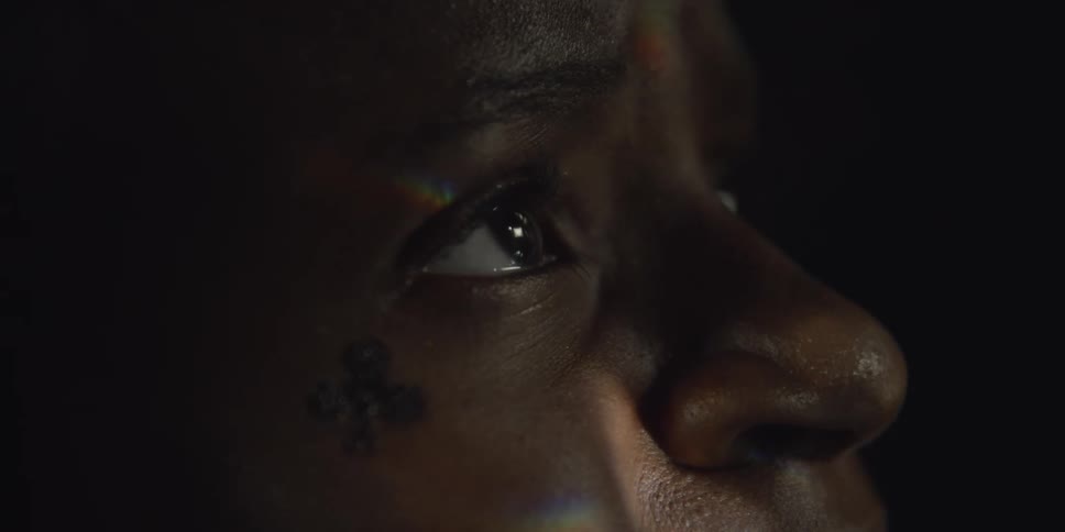 Light shines on a womans face as she looks up and blinks with sad eyes