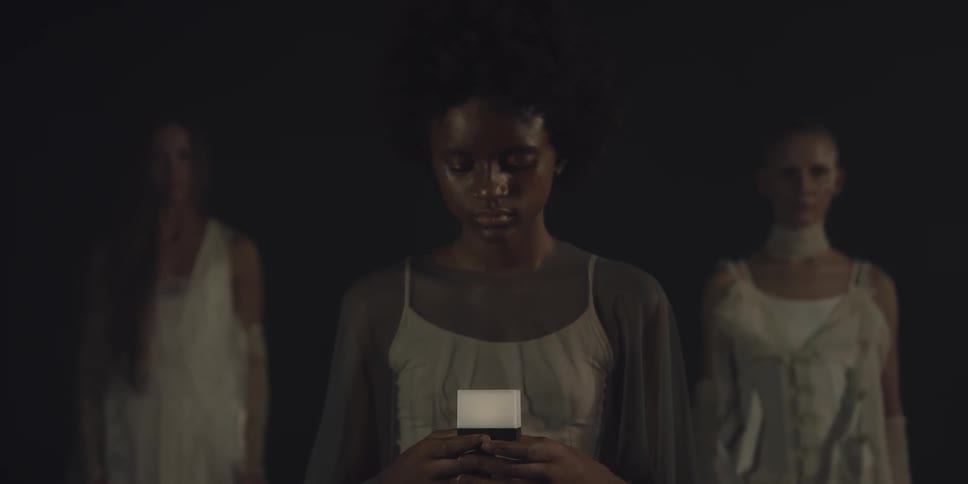 Three women stand together in the dark