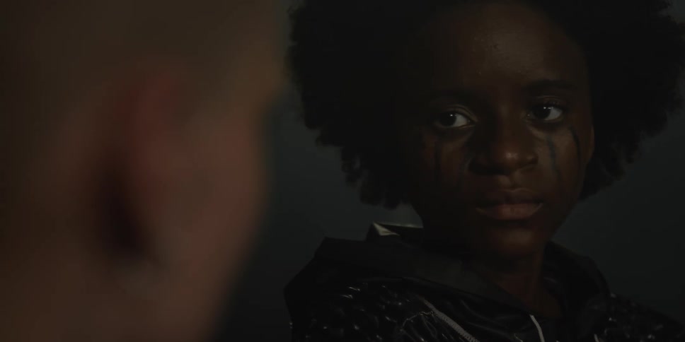 A woman's dark tears are on her face as she solemnly looks at another woman