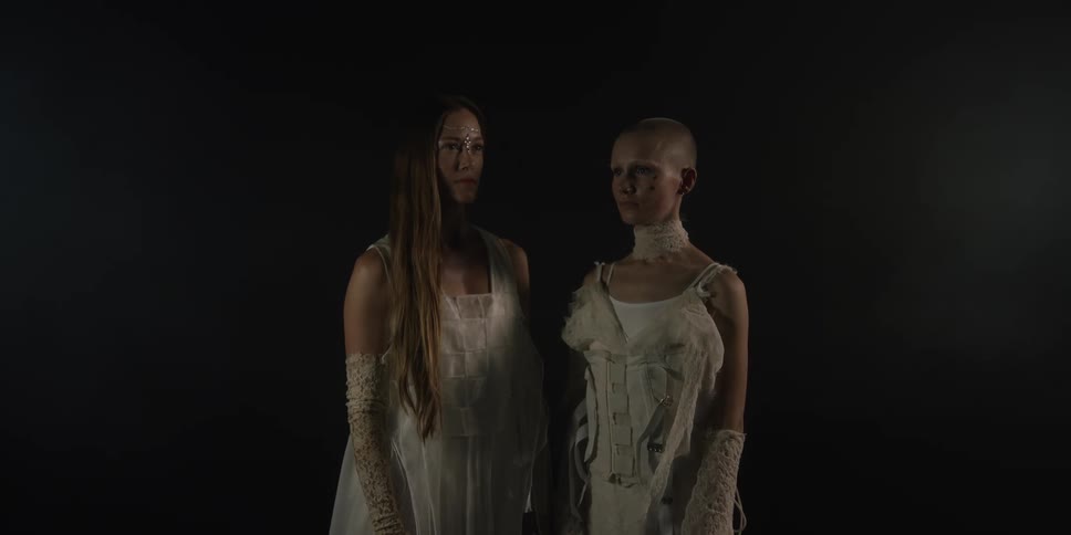 Two women are standing by eachother and wearing dresses