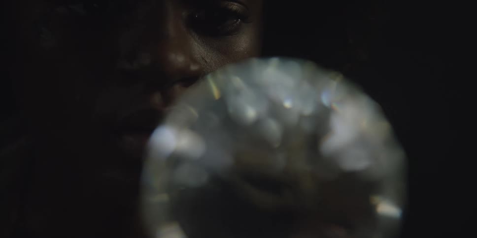 There is a young black woman looking at a diamond