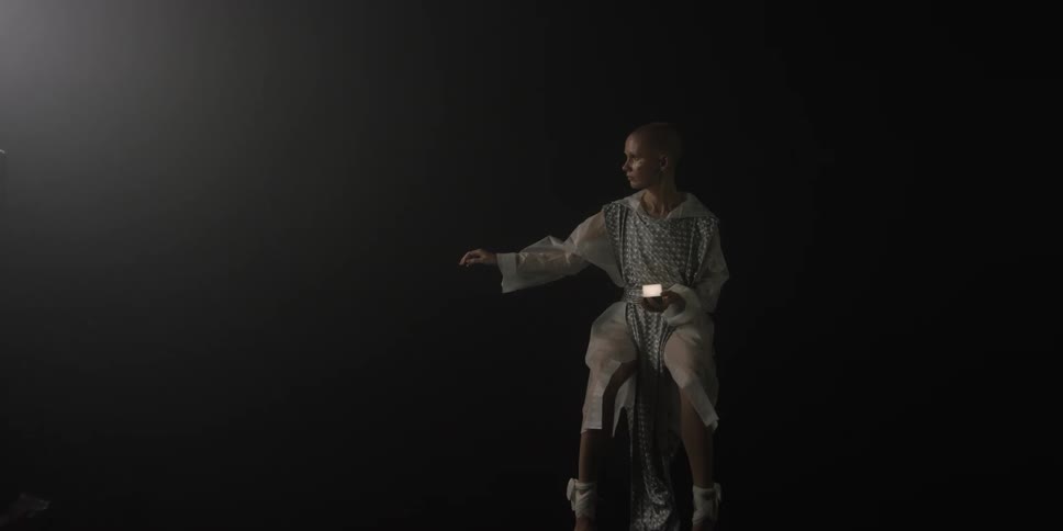 A woman walks away from another who is sitting holding a glowing light
