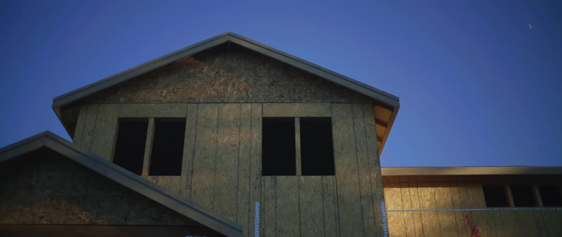 A building is being constructed and there is bare wood with no windows under a clear blue sky