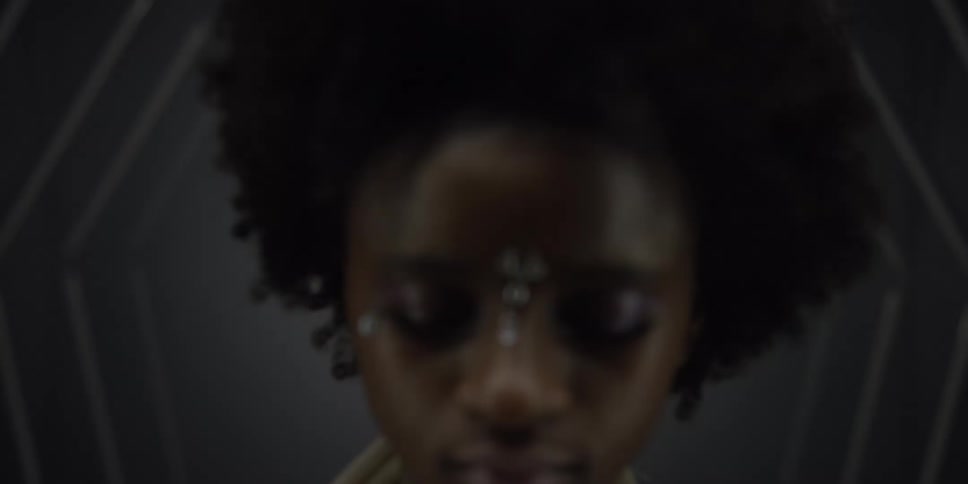 There is a young black woman that is standing and closing there eyes
