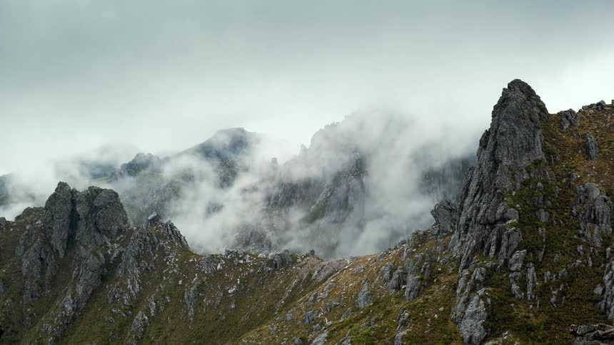 Heavy fog swirls around the peaks of a canyon