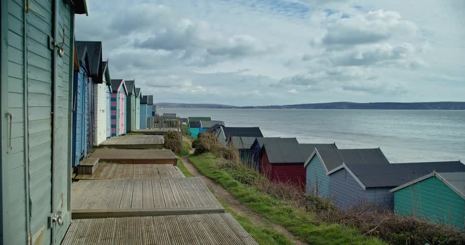 Beach huts are lined up along the coast overlooking the ocean