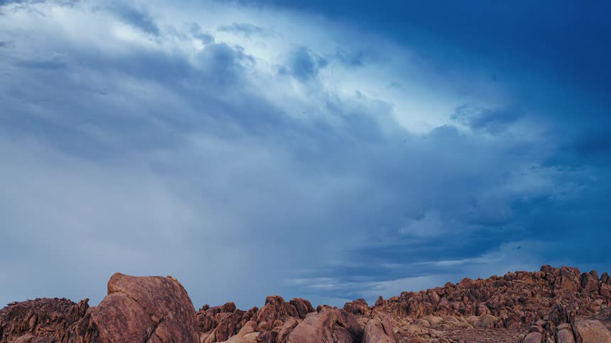 Blue clouds float over rocky hill