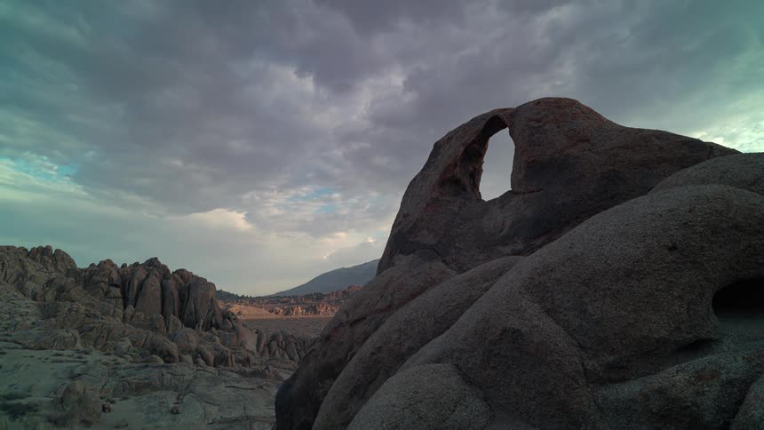 Clouds floating over an arch rock formation in nature at sunset