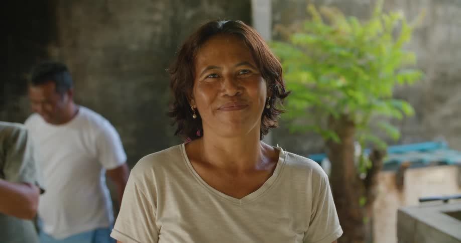 A woman smiles wide while posing outside on a patio