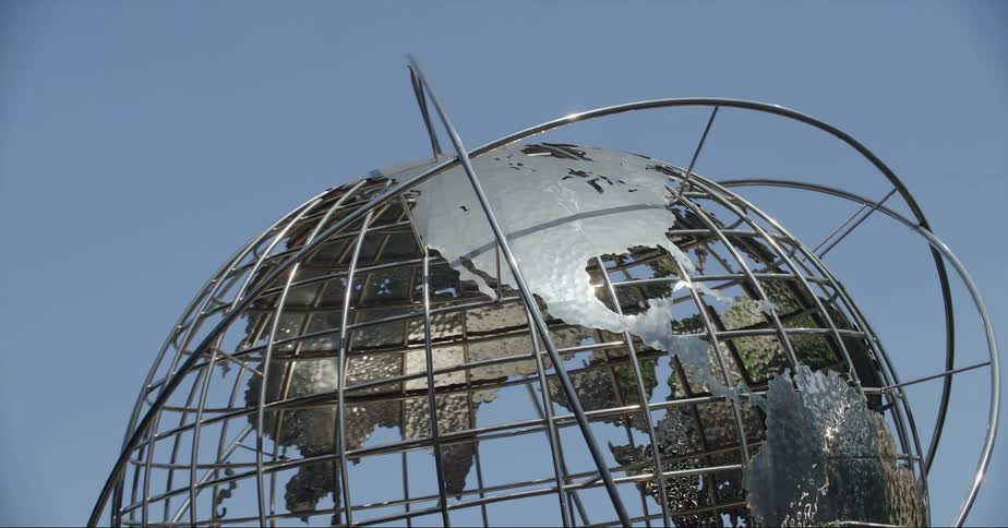 A large sculpture of a globe sits outside skyscrapers downtown