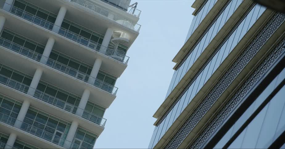 A helicopter flies swiftly past a gap between two high rise buildings