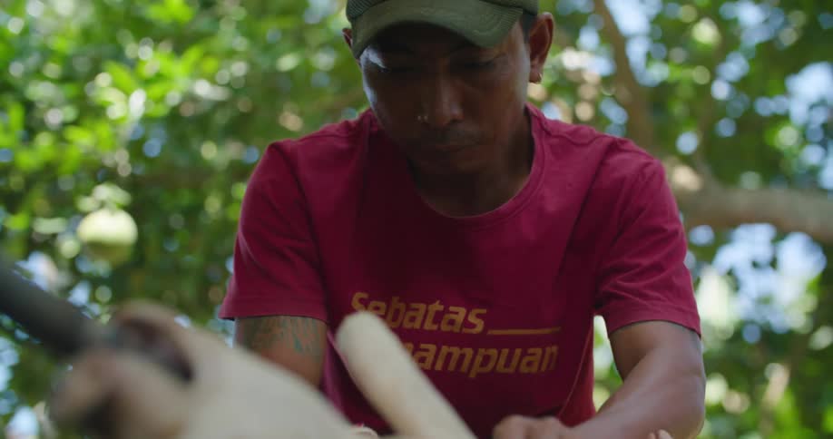 A man ties a pig to an outdoor spit