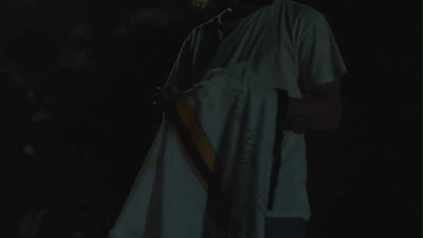 A man is outdoors and putting on his jacket