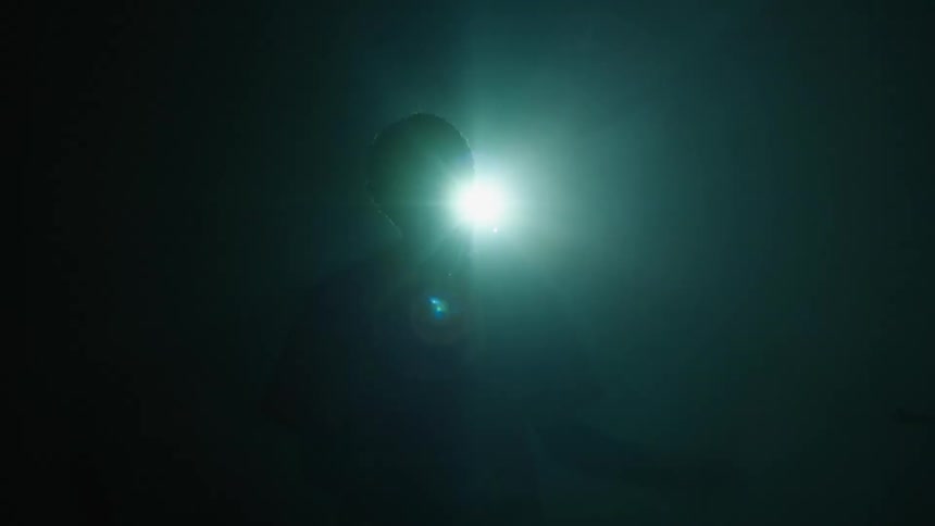 Man silhouetted against a spotlight gestures and moves