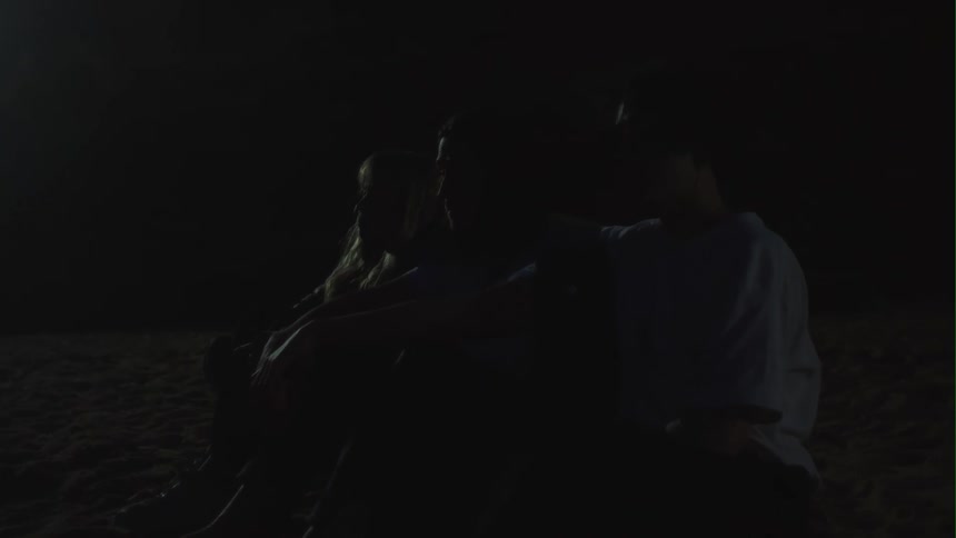 Three friends are sitting outdoors during the night time