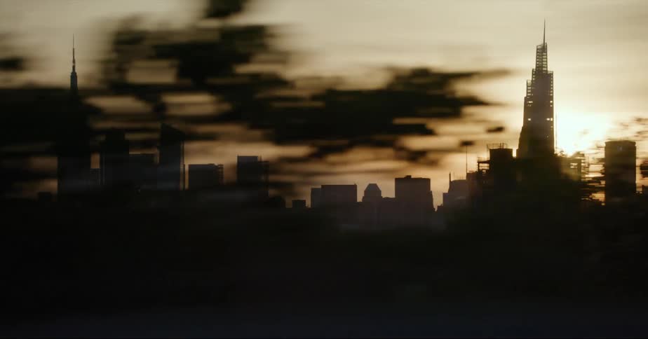 Traveling past the silhouette of the new york city skyline with the sun rising behind