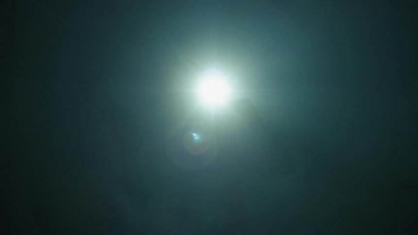 A man dances and raps while standing in front of a spotlight sillhouetted
