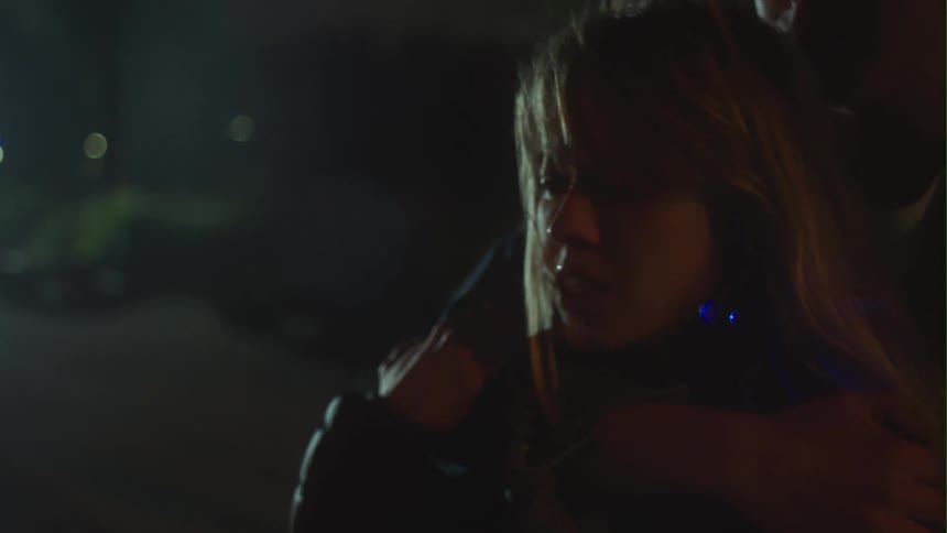 Man holds blonde woman crying in the street at night