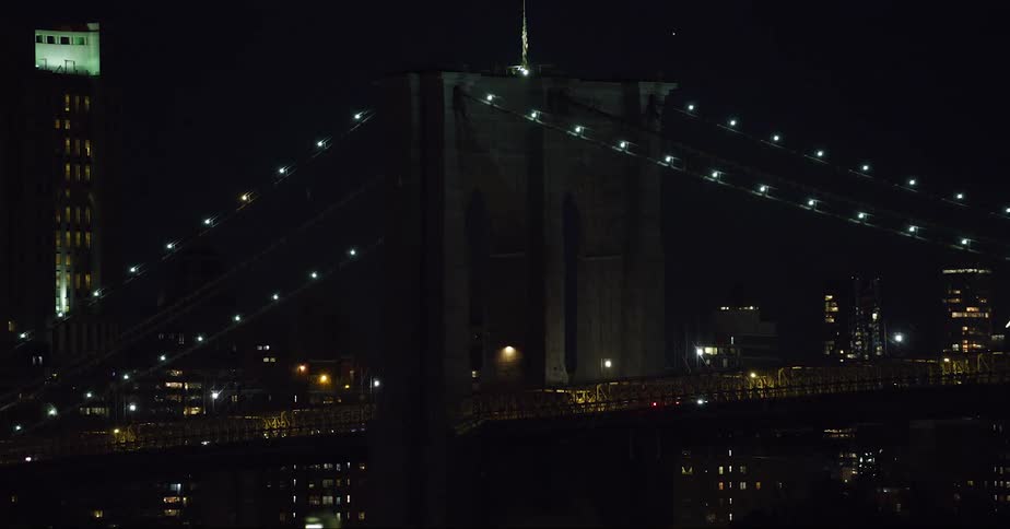 Vehicles cross the illuminated suspension bridge in the city at night