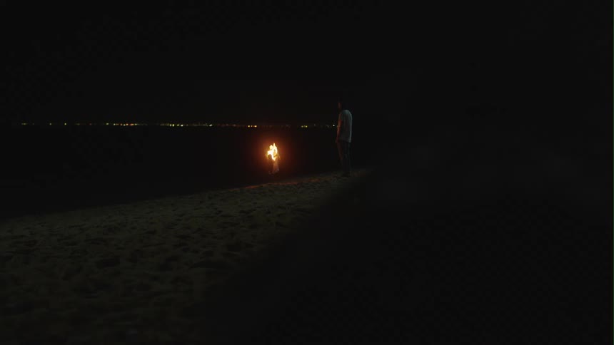 Person stands near fire on ground overlooking dark city