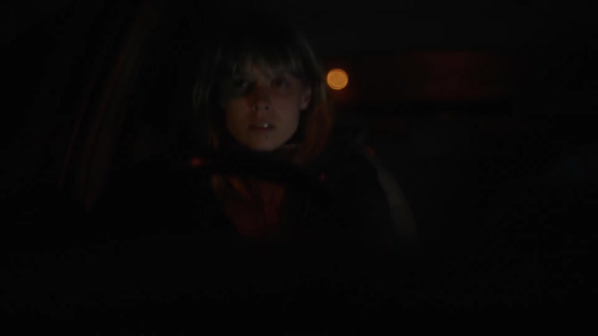 A woman holds onto the steering wheel of her car while driving at night