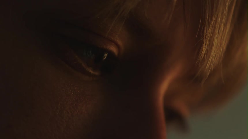 The camera takes a closeup of a womans eyes as she gazes downward and blinks