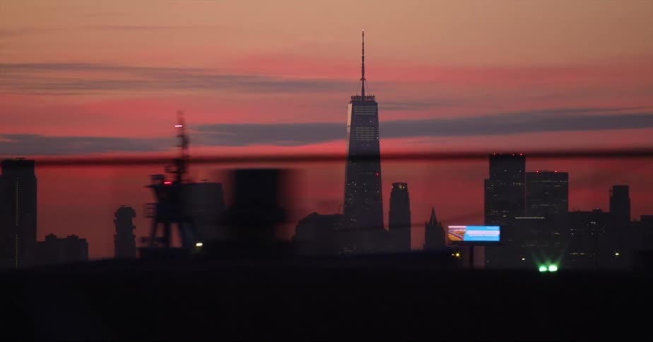 Skyscraper towering over nearby buildings stands against red sky