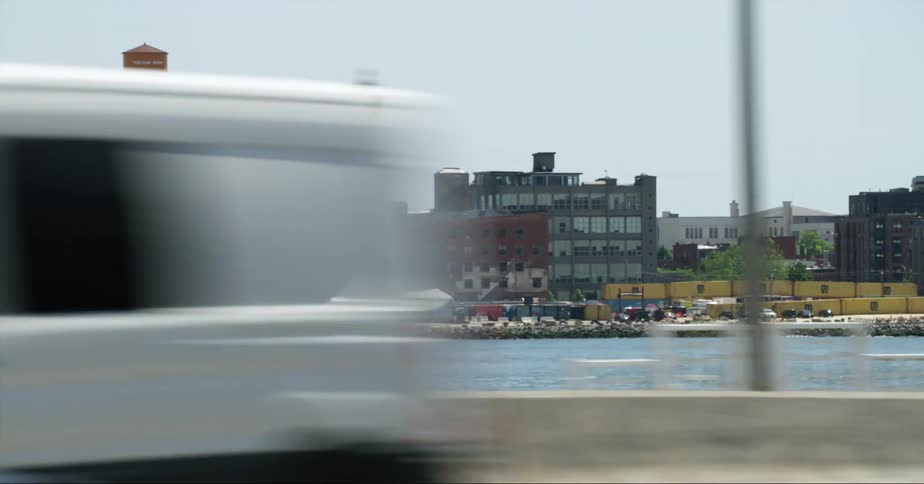 Yacht moving near the city seen from a car driving on the highway at daytime